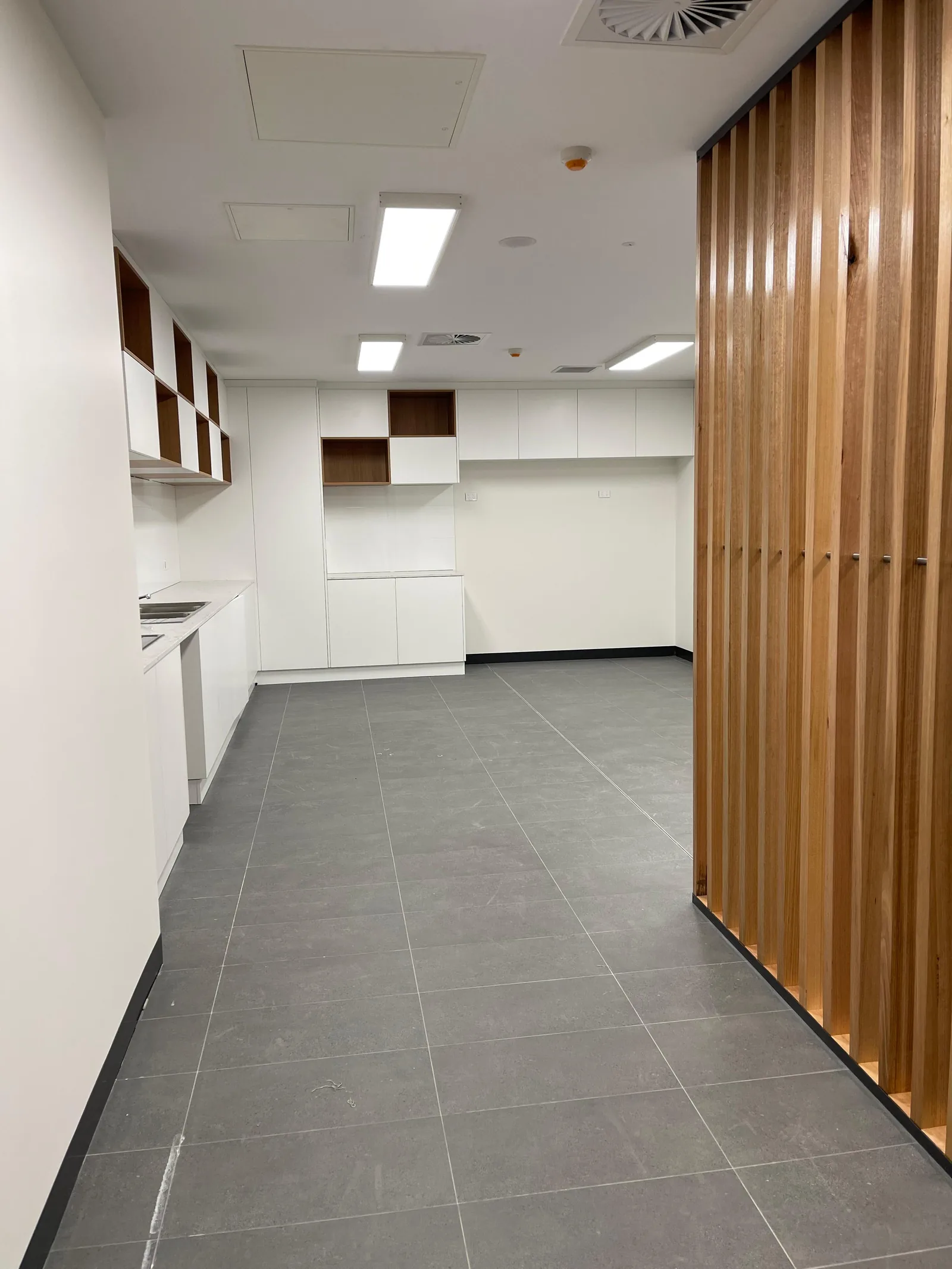 Completed large-format grey floor tiling in a commercial interior in Altona