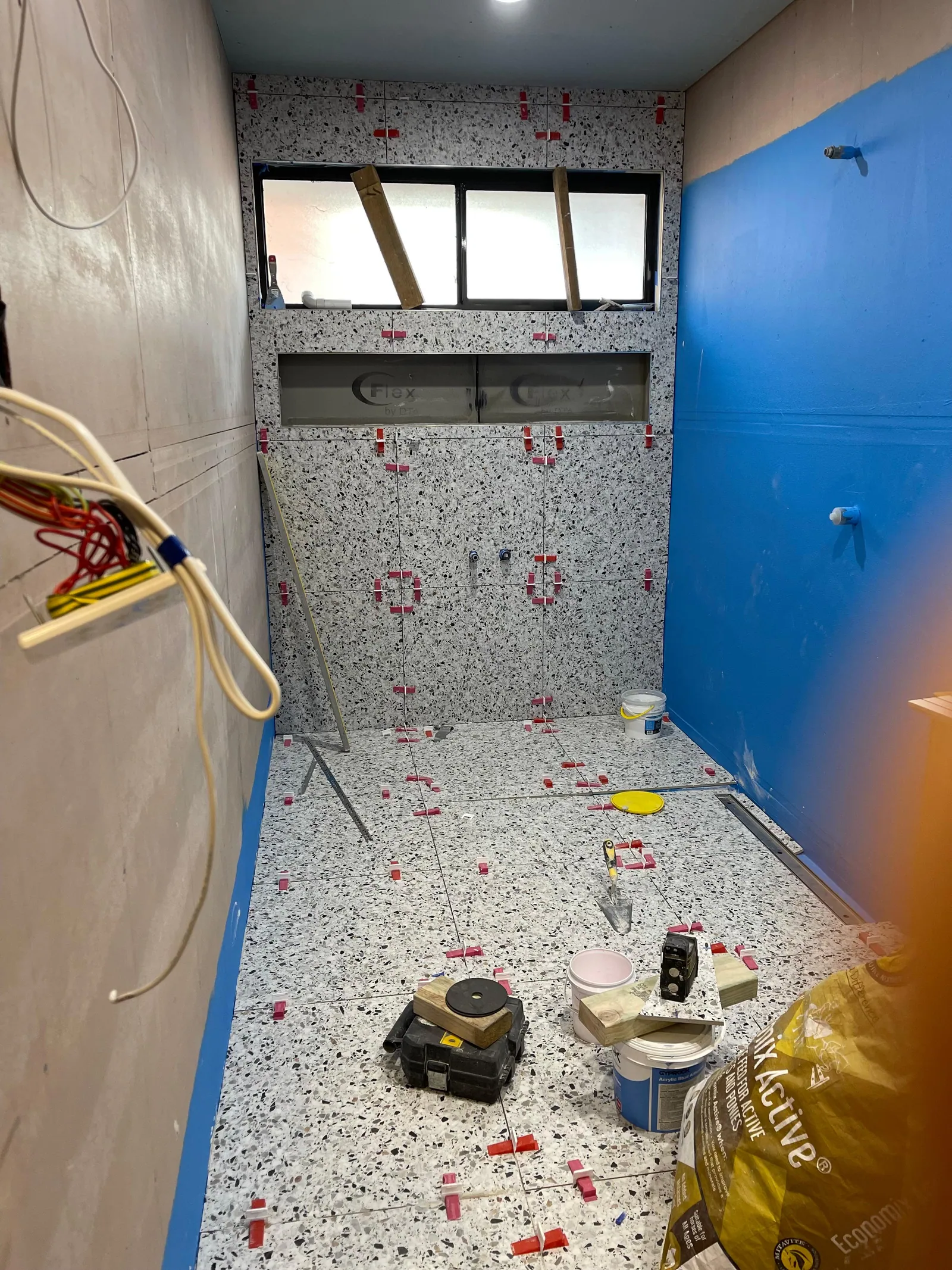 Wall tiles being installed in the wet area over the waterproofed surface