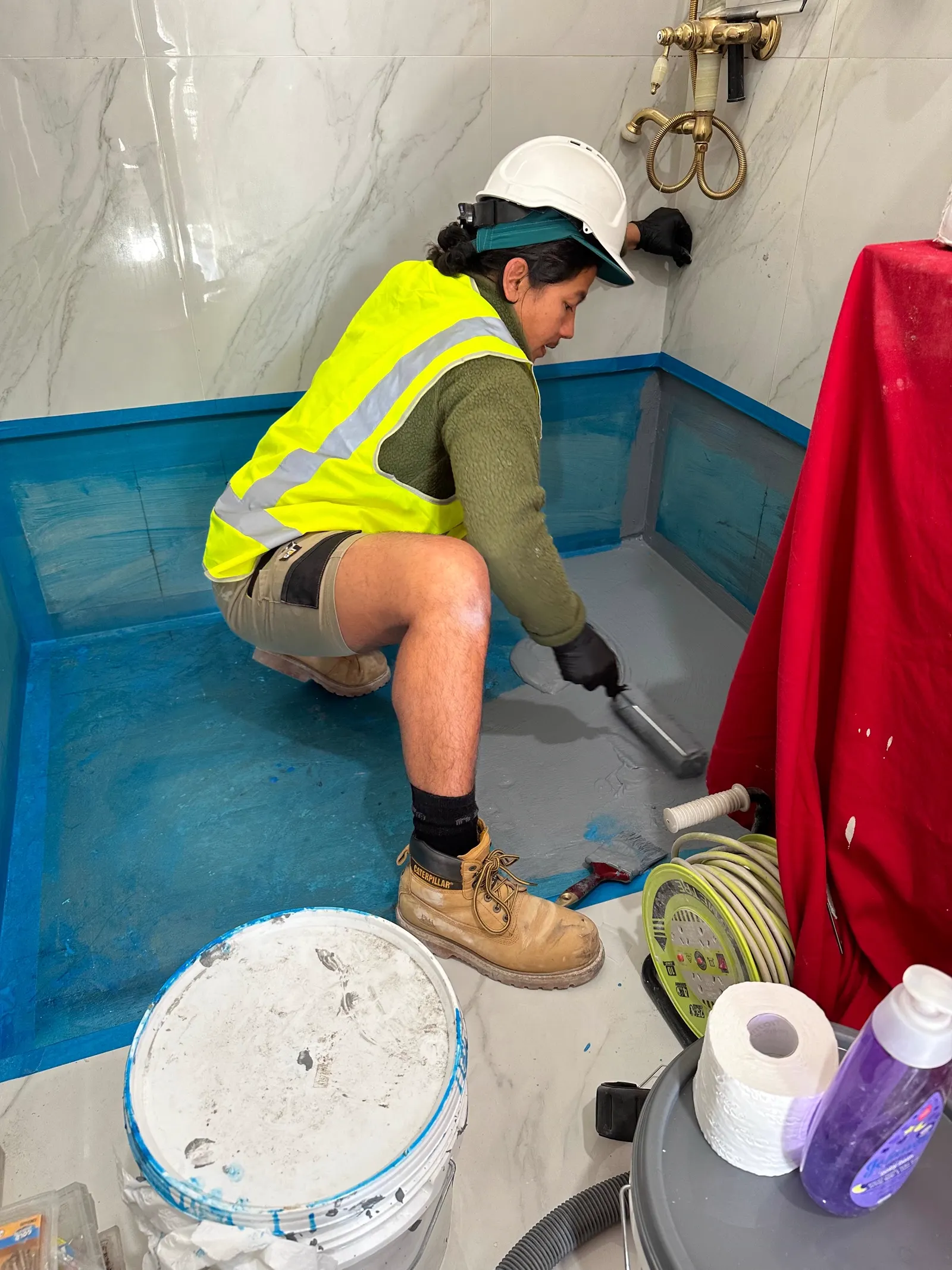 Waterproofing membrane being applied to a shower wall and floor junction before tiling