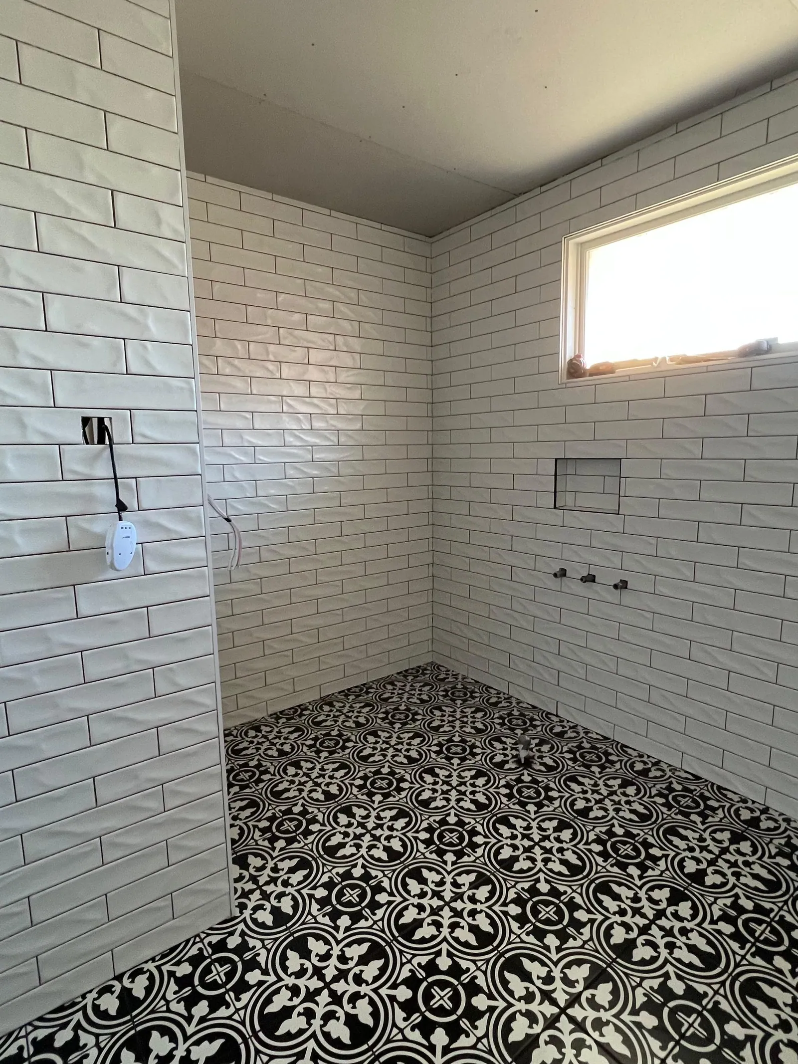 Completed bathroom with a patterned tiled floor and tiled walls