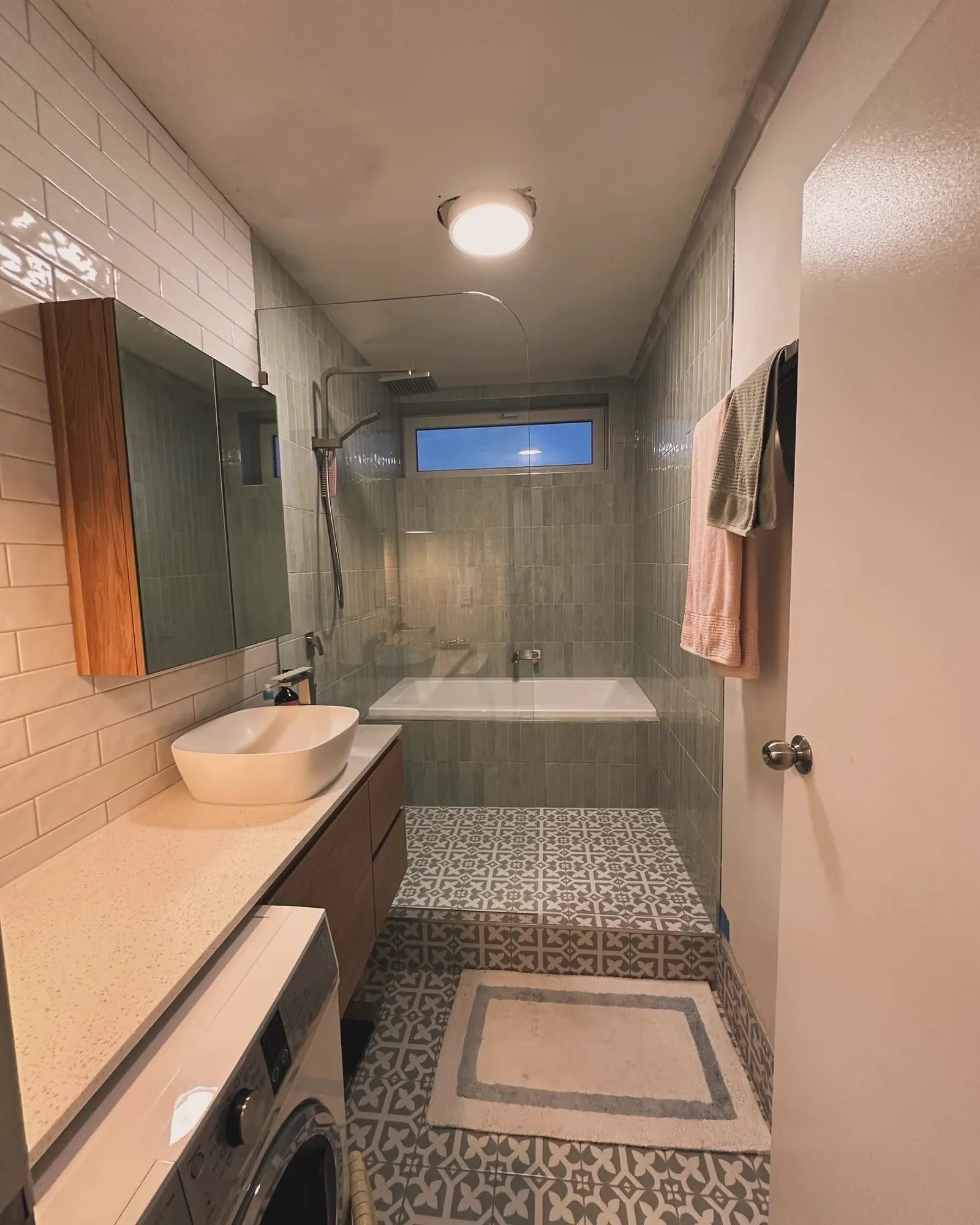 Bathroom completed by FA Tiling Group with a patterned tiled floor and fully tiled shower walls