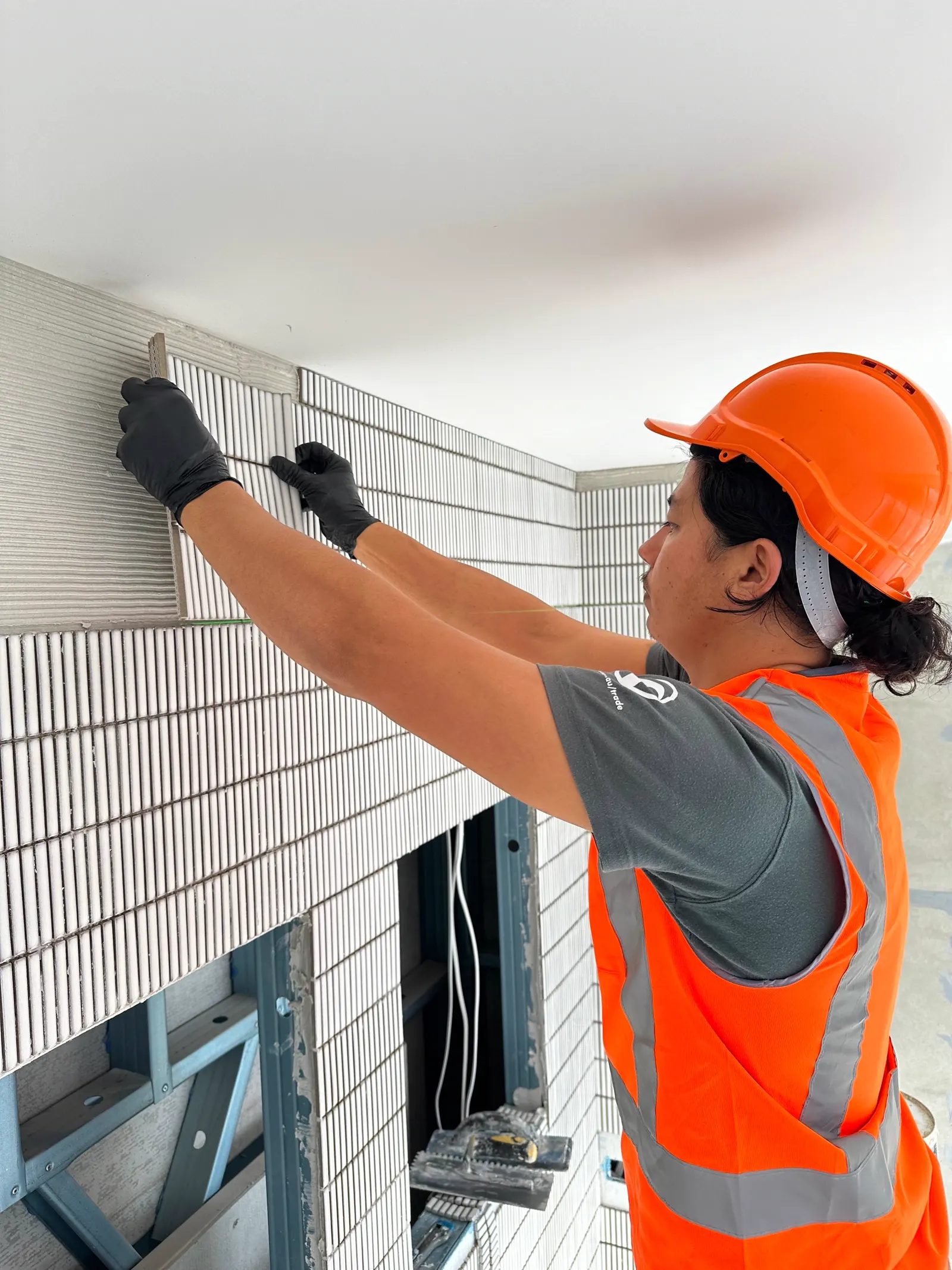 FA Tiling Group tiler setting wall tiles by hand during a bathroom installation