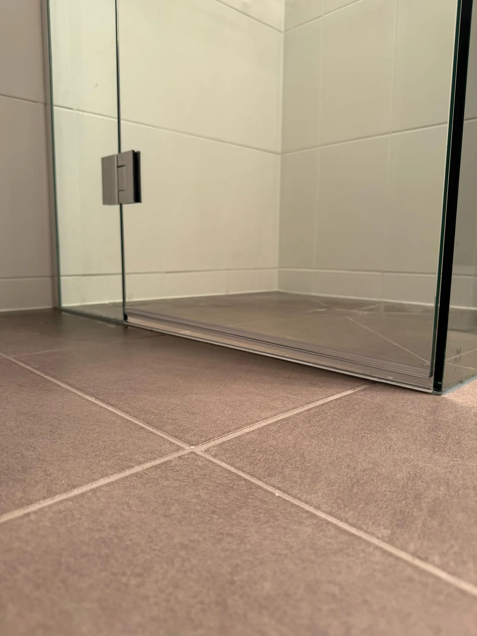 Close view of the finished shower base tiling and floor waste