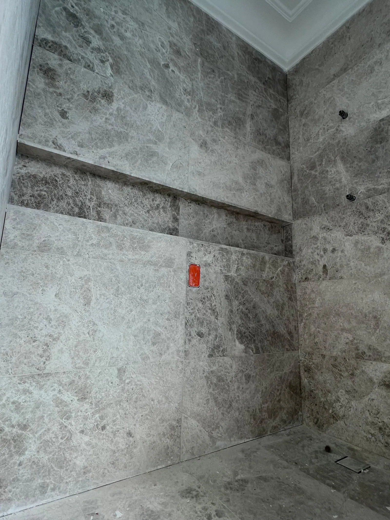 Large-format grey tiling to a wet-area wall and floor