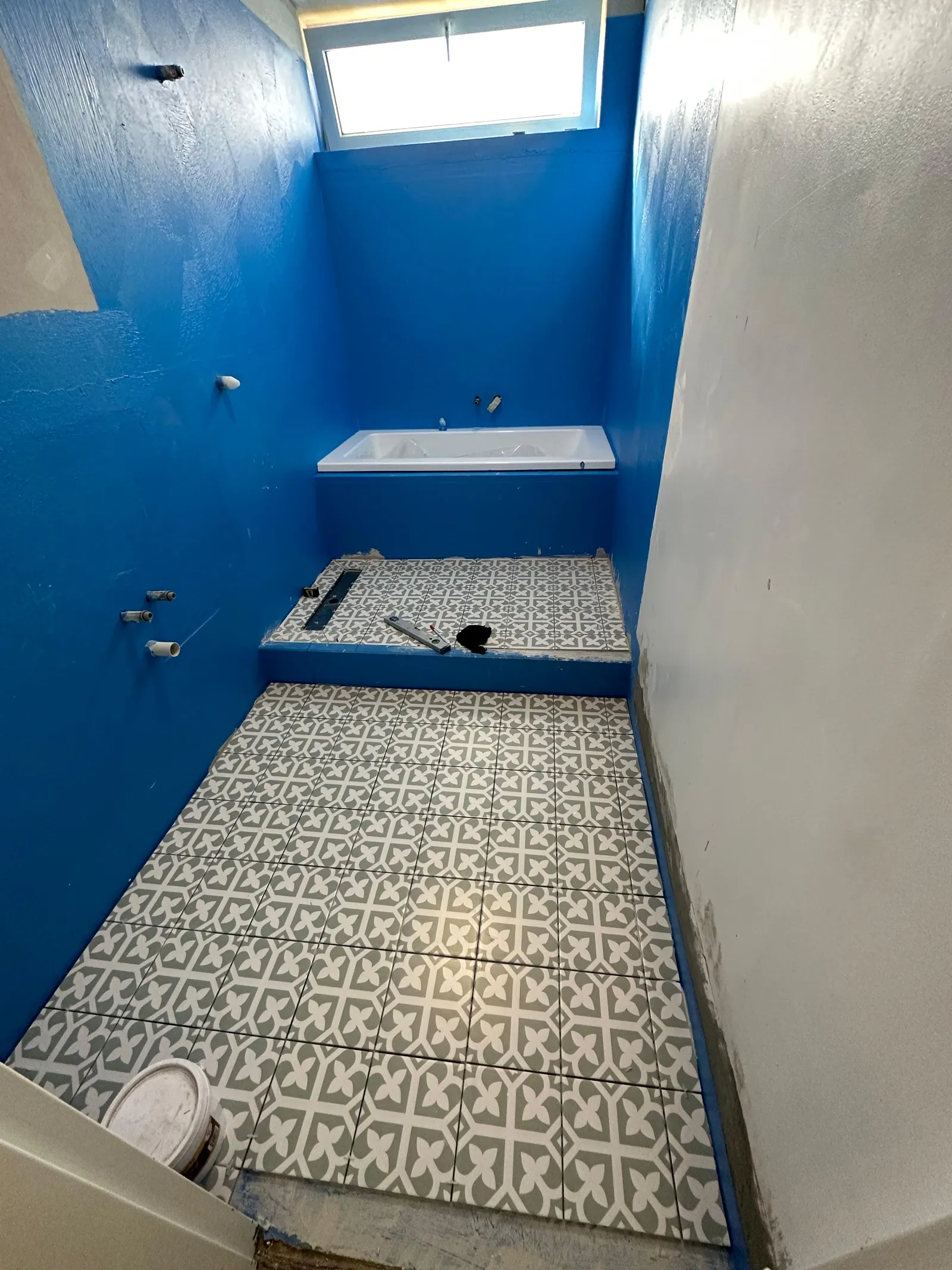Floor tiles being installed over the waterproofed bathroom floor