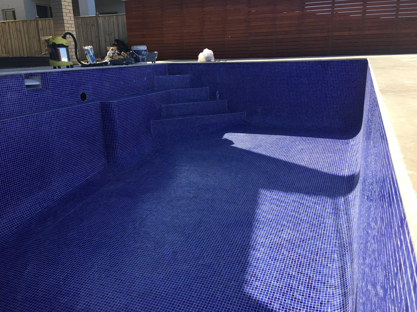 Blue and purple mosaic pool tiling viewed during installation