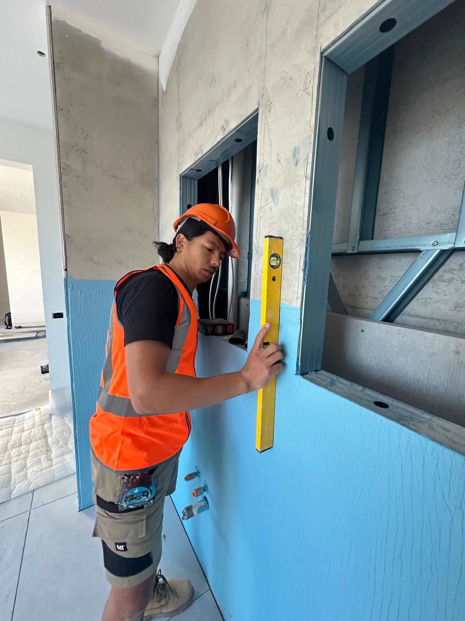 FA Tiling Group tiler checking level and set-out against a waterproofed wall before tiling
