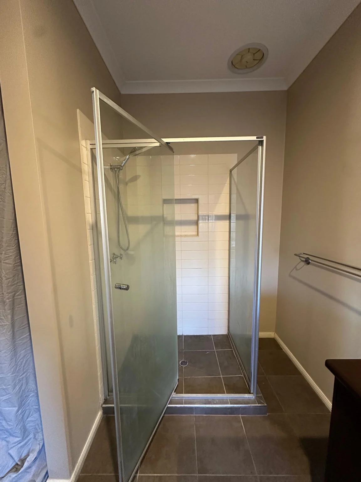 Shower before tiling, with glass enclosure and grey floor tiles