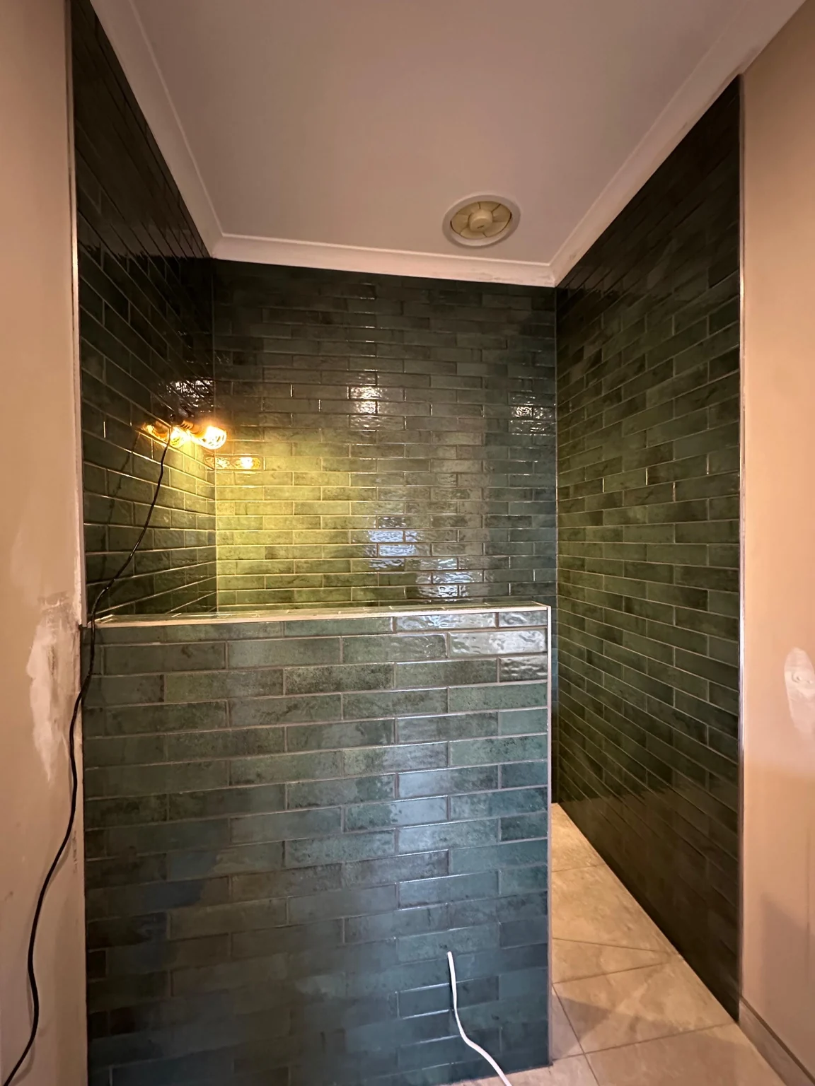 Green tiled shower walls and half-wall before final fittings