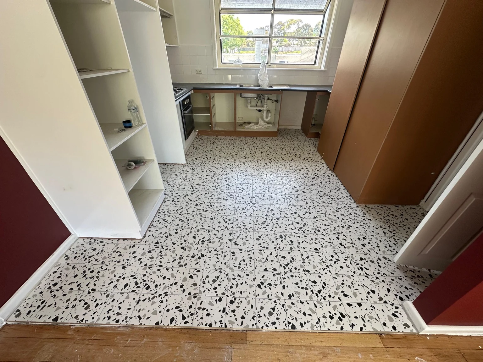 Kitchen after floor tiling with white and dark flecked terrazzo-look finish