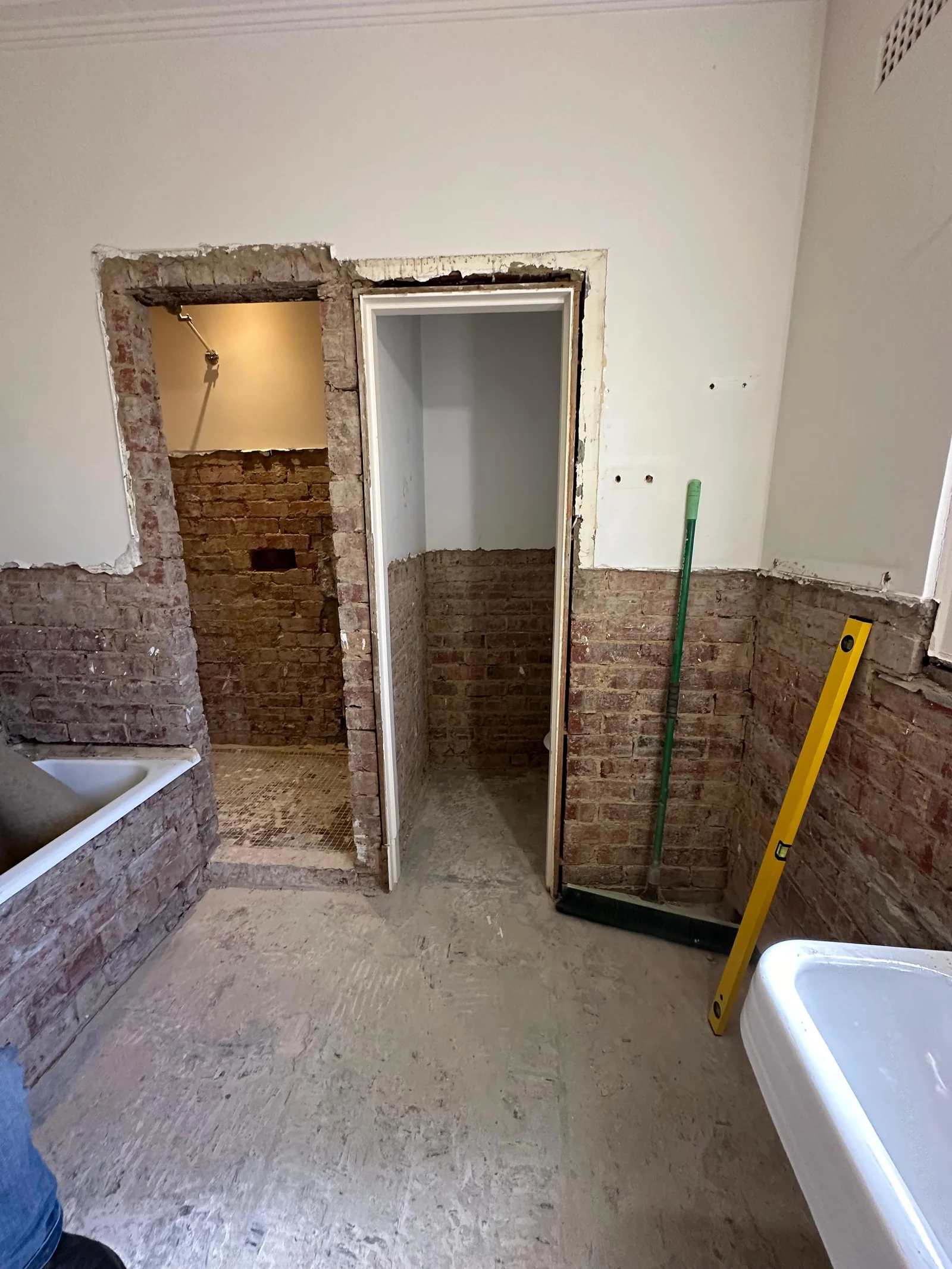 Bathroom stripped to exposed brick and bare floor before tiling