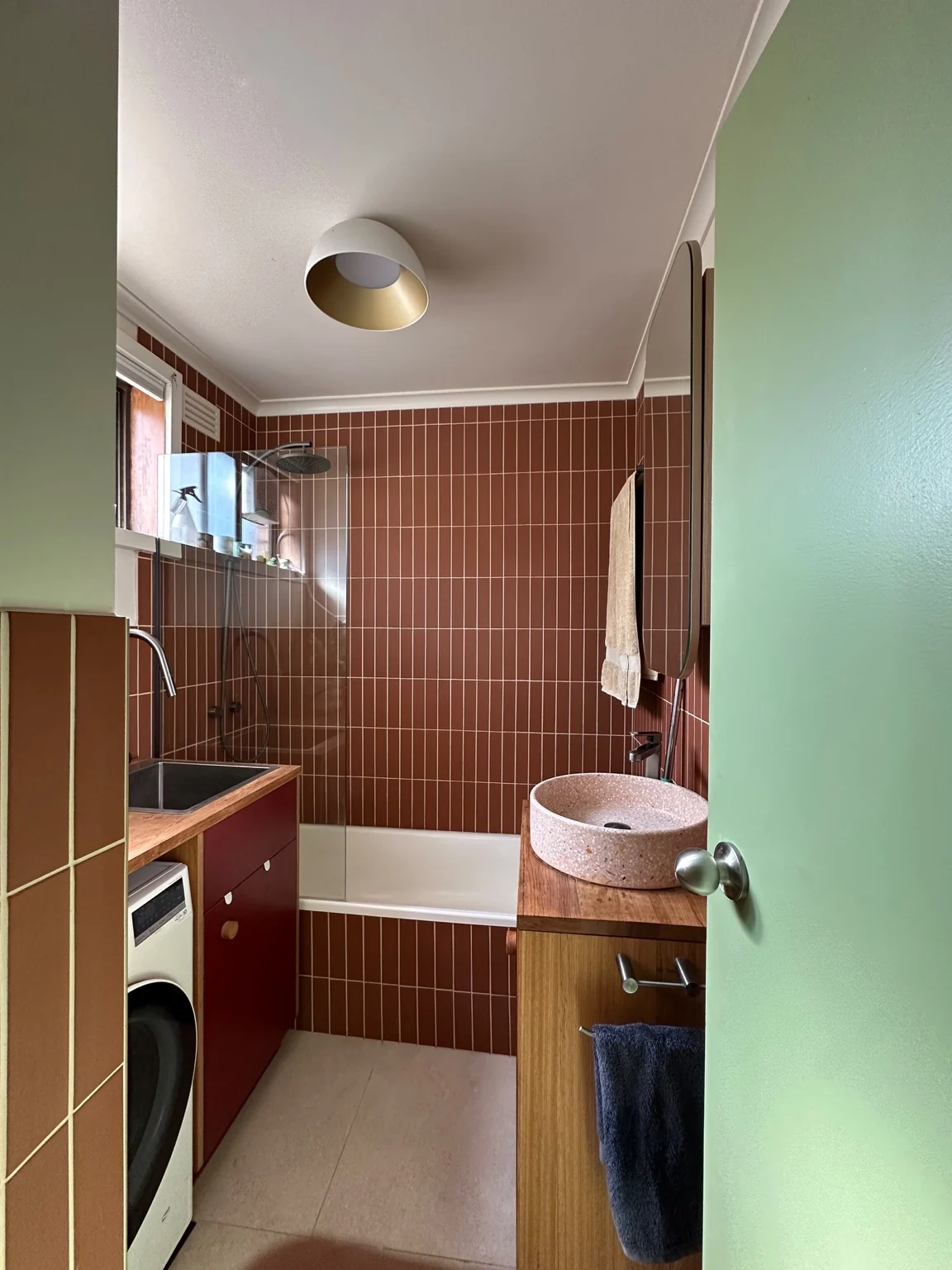 Renovated bathroom with vertical terracotta tiles, timber vanity and bath