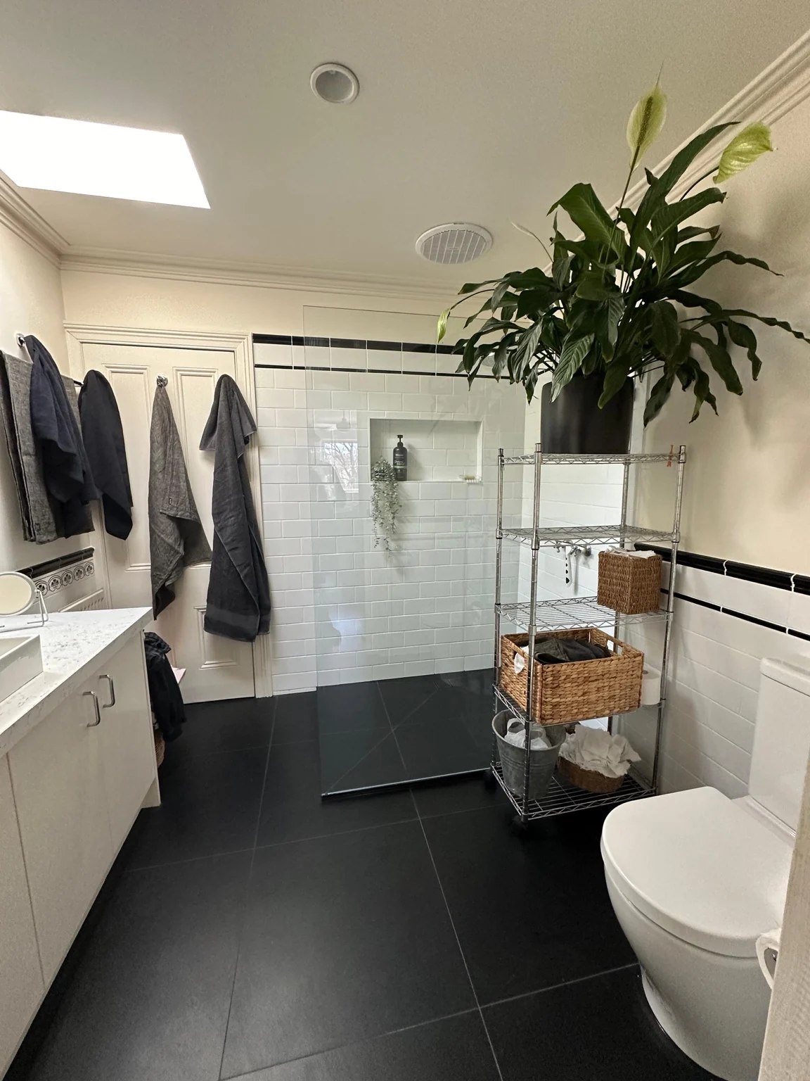 Completed white and black tiled bathroom with vanity, shower and dark floor