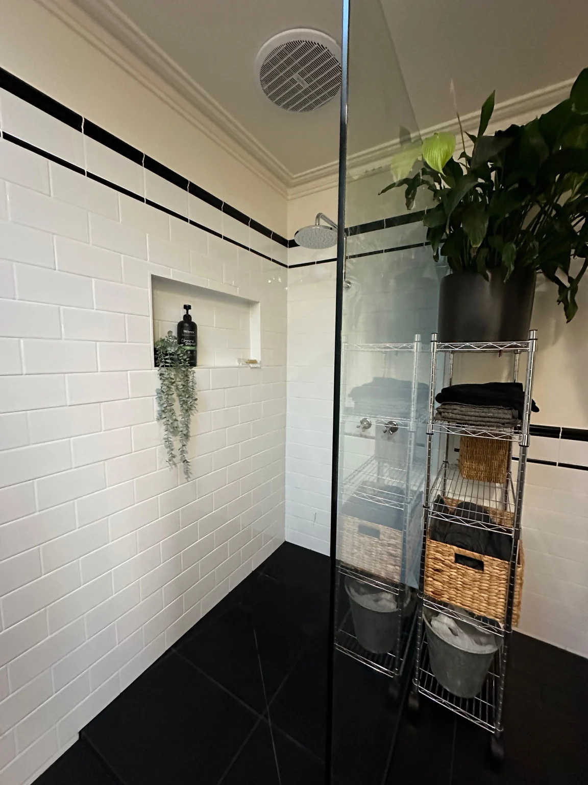 White subway tiled shower with black border, recessed niche and dark floor
